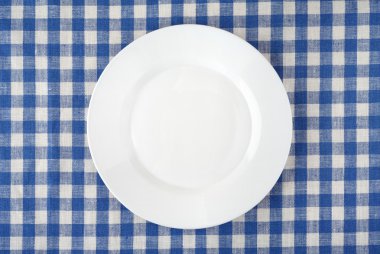 Boş beyaz plaka üzerinde damalı masa örtüsü.