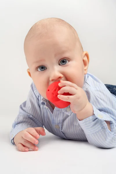 小男孩咬一个红色的玩具 — 图库照片