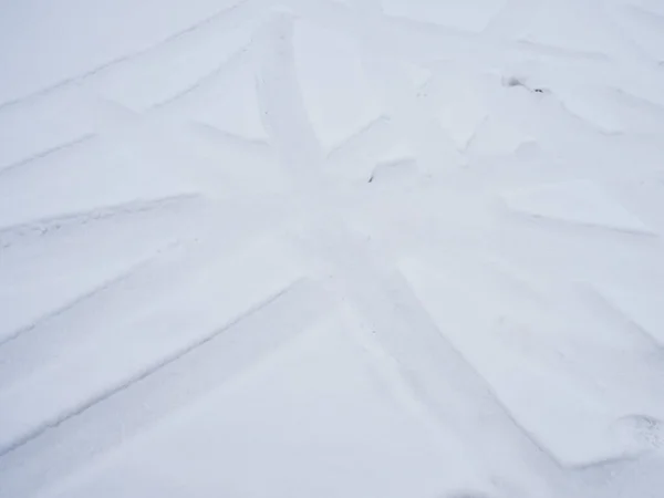 Beyaz karda kesişen araç izleri ile dikey resim