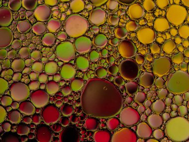 Su yüzeyinde sarı, yeşil ve kırmızı renkli yağ kabarcıkları