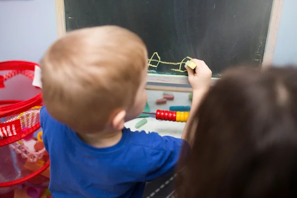 Kleiner Junge zeichnet auf einem Brett — Stockfoto