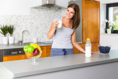 Bir bardak süt ile gülümseyen genç kadın