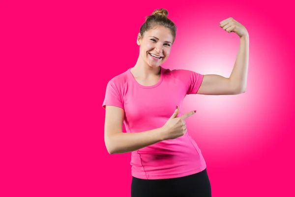 Mujer en forma señalando su bíceps —  Fotos de Stock