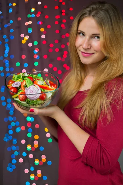 Donna sorridente con insalata in forma su sfondo natalizio — Foto Stock