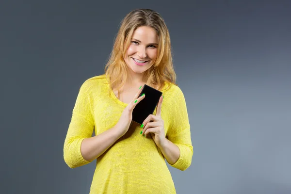Usměvavá mladá žena ukazující chytrý telefon s prázdný displej — Stock fotografie