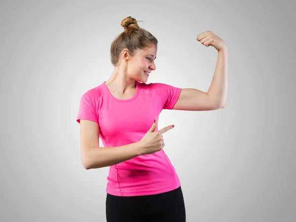 Muskulöse Frau zeigt auf ihren Bizeps — Stockfoto