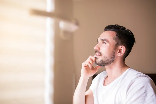 Buen hombre barbudo teniendo conversación telefónica en su dormitorio — Foto de Stock