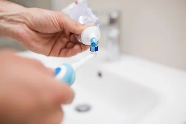 Homem derramando pasta de dentes em uma escova de dentes — Fotografia de Stock