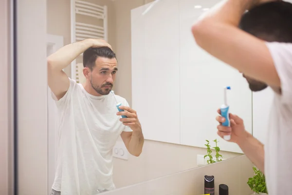 Young man with electric toothbrush — Stock Photo, Image