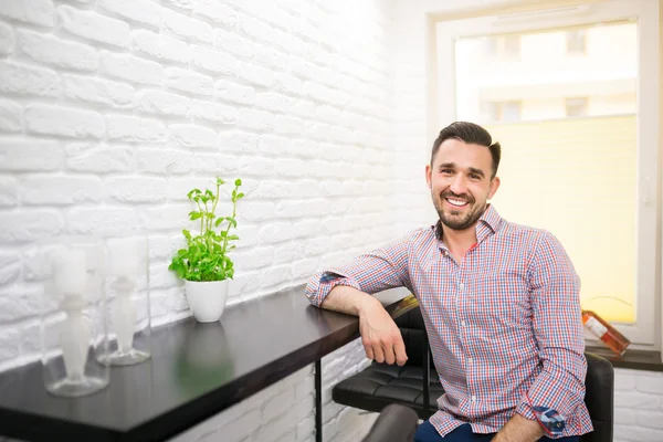 Sonriente hombre guapo sentado junto a la mesa — Foto de Stock