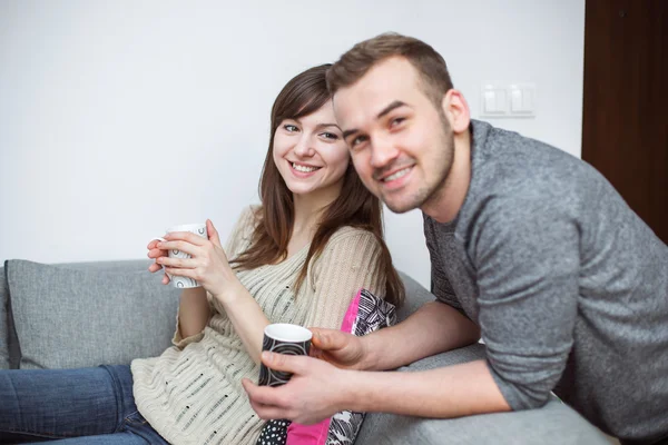 Lachende paar met koffie in de woonkamer — Stockfoto