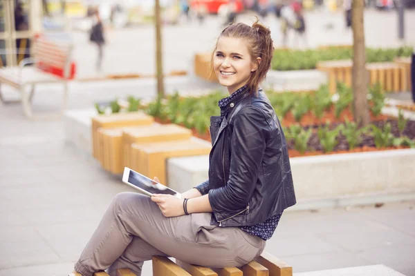 Mujer sonriente en un banco navegando por la red — Foto de Stock