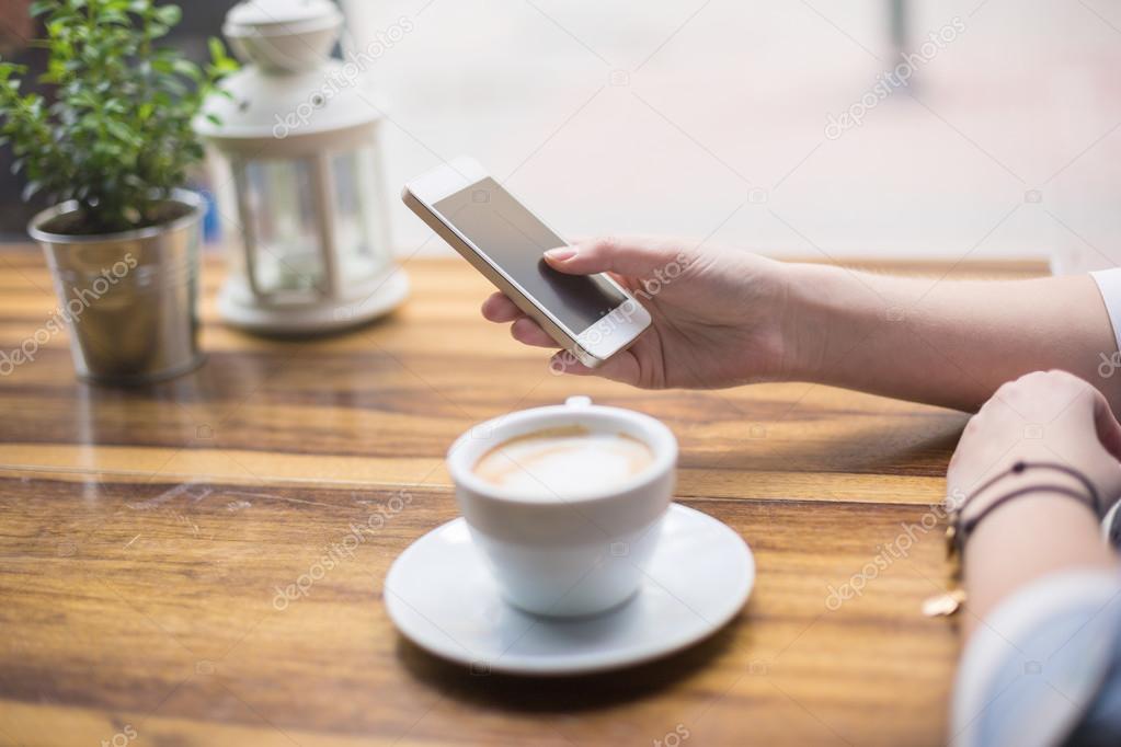 Texting on smart phone while having coffee