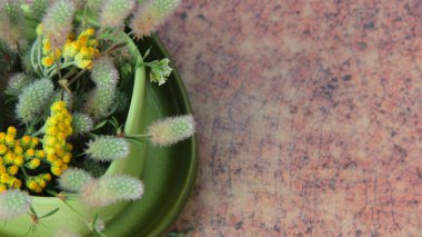 Masanın üzerinde duran bir fincan içindeki kır çiçekleri.