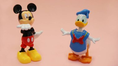 Mickey Mouse ve Donald Duck hafif bir arkaplanda durur ve duygularını elleriyle gösterirler.