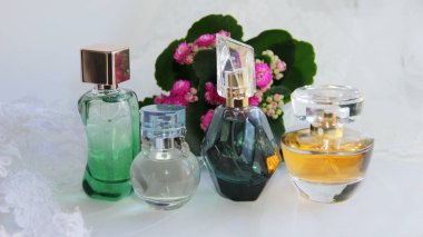 Çiçek ve dantelli beyaz arka planda bir sürü farklı parfüm şişesi ya da eau de tuvalet.