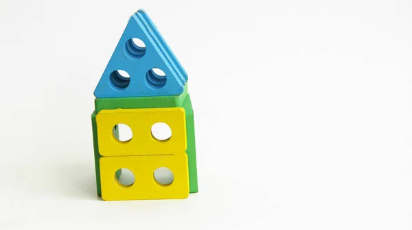 家は様々な色や形の子供用の木製のブロックで作られています カラフルな数字が白い背景に家の中に積み重なっています — ストック写真