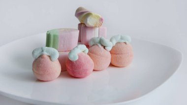 Beyaz arka planda cam bir vazoda şekerleme. Vazodaki farklı şekillerde şekerlemeler. Şekerler.