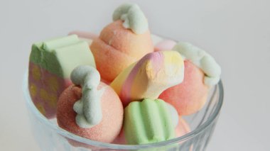 Beyaz arka planda cam bir vazoda şekerleme. Vazodaki farklı şekillerde şekerlemeler. Şekerler.