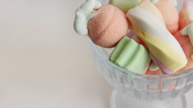 Beyaz arka planda cam bir vazoda şekerleme. Vazodaki farklı şekillerde şekerlemeler. Şekerler.