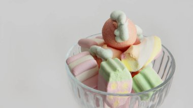 Beyaz arka planda cam bir vazoda şekerleme. Vazodaki farklı şekillerde şekerlemeler. Şekerler.