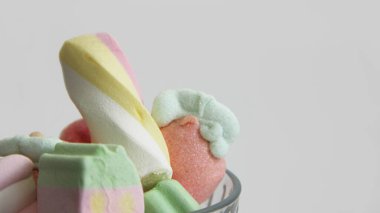 Beyaz arka planda cam bir vazoda şekerleme. Vazodaki farklı şekillerde şekerlemeler. Şekerler.