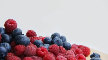 Beyaz arka planda taze ahududu ve yaban mersini. Yaban mersini ve ahududu ağaçtan bir arka planda.