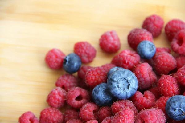 Fresh raspberries and blueberries on a white background close-up. wild summer berries blueberries and raspberries on a wooden background