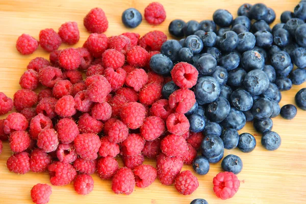 Fresh raspberries and blueberries on a white background close-up. wild summer berries blueberries and raspberries on a wooden background