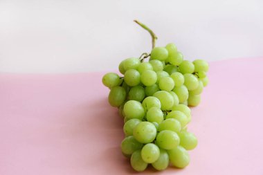 Açık arkaplanda bir demet yeşil üzüm.