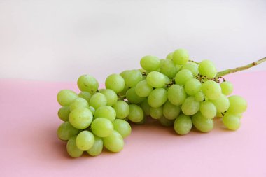 Açık arkaplanda bir demet yeşil üzüm.