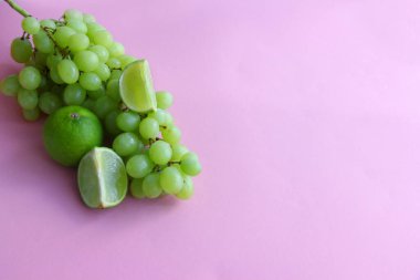 Bir demet yeşil üzüm ve limon, parlak bir arka planda limon dilimleri.