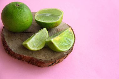Parlak bir arka planda, ahşap bir tabakta limon ve sulu limon dilimleri.