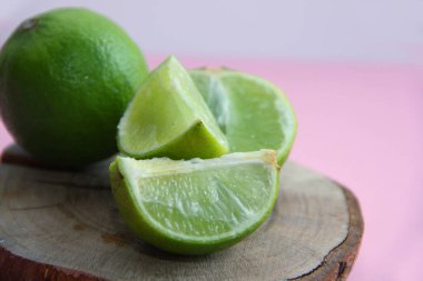 Parlak bir arka planda, ahşap bir tabakta limon ve sulu limon dilimleri.