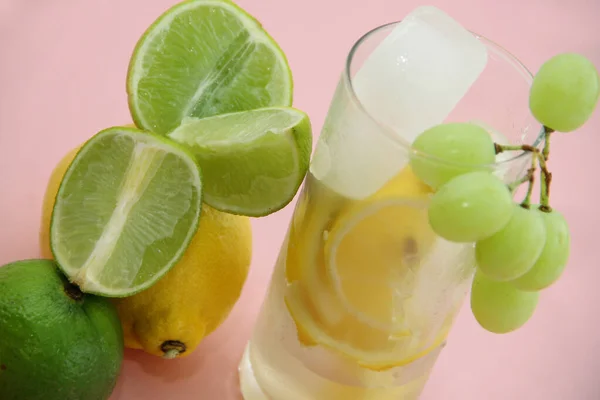レモンとライムとミントのカクテルレモンとライムとミントのカクテル ピンクの背景にライムとレモン カットされたライムスライスとレモン — ストック写真