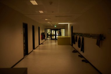 Boş okul koridoru, duvarında ceketler asılı.