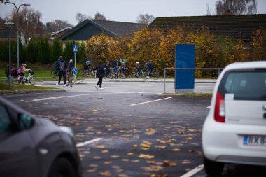 Çocuklar bulutlu bir günde okuldan eve yürüyerek ve bisikletle dönüyorlar.