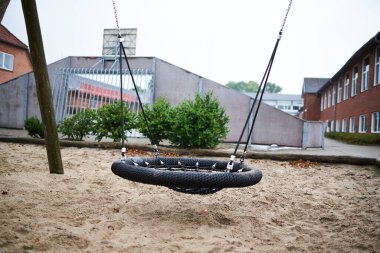 Yağmurlu bir günde çocuk parkında siyah bir salıncak.