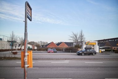 Danimarka 'da işlek bir yolda sarı bir otobüs durağı.