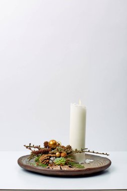 Masadaki ahşap kasede beyaz mum süslemesi