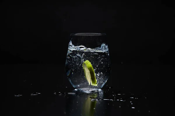 a clear glass with lemonade on a black background