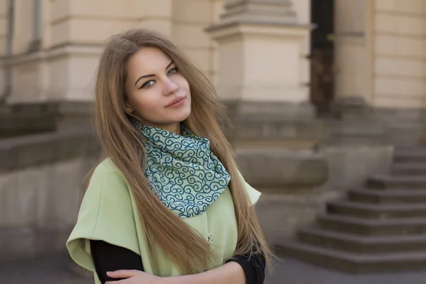 Smiling young woman in a green coat — Stock Photo, Image