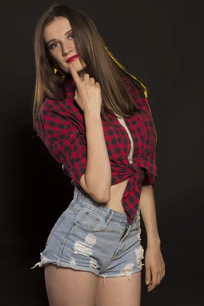 Schöne junge Frau in Jeans-Shorts und kariertem Hemd — Stockfoto