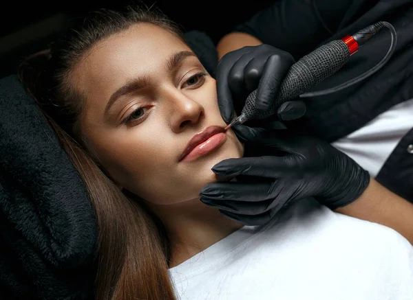 Beauty master applying lip permanent ink at the beauty salon. Closeup shot