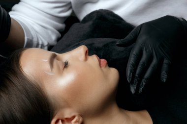 Eldivenli güzellik uzmanı kaşlarını kalıcı işlemden önce beyaz işaret koyuyor.