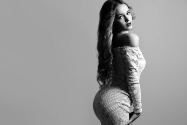 Dalgalı saçlı baştan çıkarıcı sarışın kadın çıplak omuzlu şık bir elbise giyiyor. Mesaj için yer var. Siyah beyaz portre