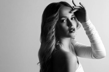 Uzun kıvırcık saçlı çekici sarışın kadın, çıplak omuzlu şık bir elbise giyiyor. Boşluk. Siyah beyaz portre