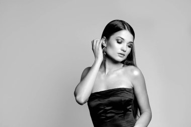 Gri bir arka plan üzerinde çıplak omuzları ve güzel makyajı olan harika bir genç kadının siyah beyaz portresi. Tex için boşluk