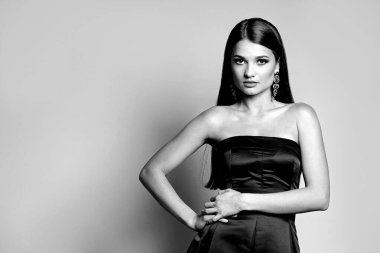 Gri bir arka plan üzerinde çıplak omuzları ve güzel makyajı olan muhteşem genç bir kadının siyah beyaz portresi. Tex için boşluk