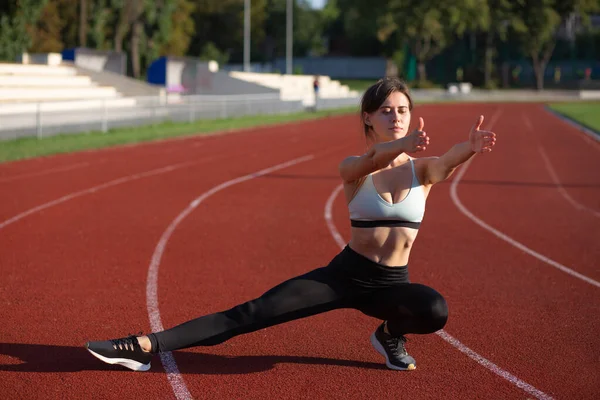 Athlete woman wears sport apparel warms up before cardio workout at the staduim